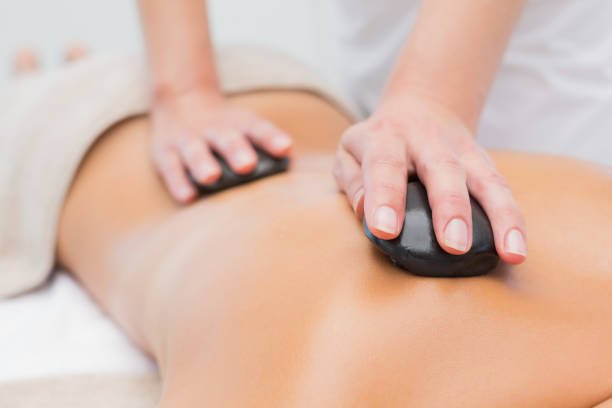 Close up of a beautiful young woman receiving stone massage at spa center